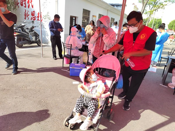 志愿者为采样群众照看幼儿.png